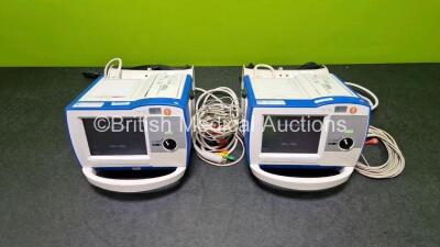 2 x Zoll R Series Plus Defibrillators / Monitors (Both Power Up) Including ECG and Printer Options with 2 x 3 Lead ECG Leads (Both Damaged Casings - See Photos), 2 x Paddle Leads, 2 x Power Cords and 2 x Lithium Ion Rechargeable Batteries *SN AF13B027383 - 2