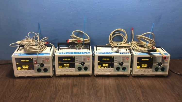 4 x Zoll M Series Defibrillators with Pacer and ECG Options with 4 x Paddle Leads, 4 x 3 Lead ECG Leads and 4 x Batteries (All Power Up When Plugged i