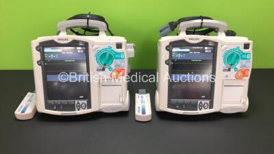 2 x Philips MRx Defibrillators Including Pacer, ECG and Printer Options with 2 x Philips M3538A Batteries, 2 x Philips M3539A Modules, 2 x Paddle Leads and 2 x Philips M3725A Test Loads (Both Power Up)