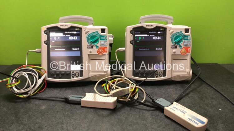 2 x Philips MRx Defibrillators Including Pacer, ECG and Printer Options with 2 x Philips M3539A Power Adapters and 2 x Philips M3538A Batteries 2 x Paddle Lead, 2 x Philips M3725A Test Loads and 2 x 3 Lead ECG Leads (Both Power Up)