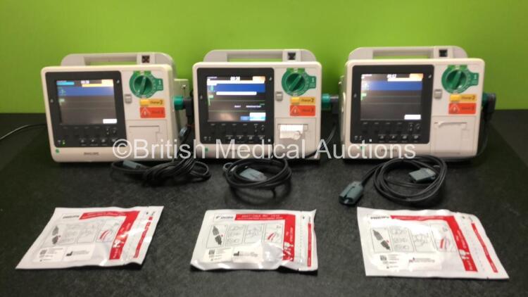 3 x Philips Heartstart XL+ Defibrillators Including ECG and Printer Options with 3 x Paddle Leads, 3 x Philips Multifunction Electrode Pads *2 Expired, 1 in Date* and 3 x Batteries (All Power Up)