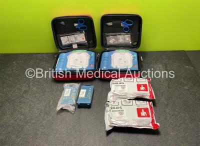 2 x Philips Heartstart HS1 Defibrillators with 4 x Batteries and 4 x Philips REF M5071A Defibrillator Pads *2 Unused* in Carry Cases (Both Power Up)