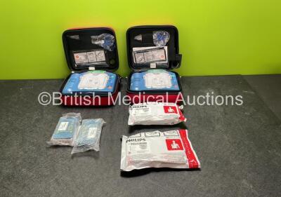 2 x Philips Heartstart HS1 Defibrillators with 4 x Batteries and 4 x Philips REF M5071A Defibrillator Pads *2 Unused* in Carry Cases (Both Power Up)