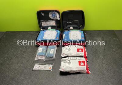 2 x Philips Heartstart HS1 Defibrillators with 4 x Batteries and 4 x Philips REF M5071A Defibrillator Pads *2 Unused* in Carry Cases (Both Power Up)