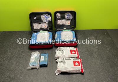 2 x Philips Heartstart HS1 Defibrillators with 4 x Batteries and 4 x Philips REF M5071A Defibrillator Pads *2 Unused* in Carry Cases (Both Power Up)