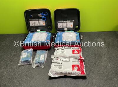 2 x Philips Heartstart HS1 Defibrillators with 4 x Batteries and 4 x Philips REF M5071A Defibrillator Pads *2 Unused* in Carry Cases (Both Power Up)