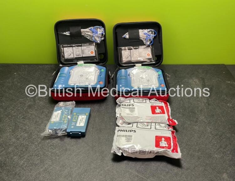 2 x Philips Heartstart HS1 Defibrillators with 4 x Batteries and 4 x Philips REF M5071A Defibrillator Pads *2 Unused* in Carry Cases (Both Power Up)