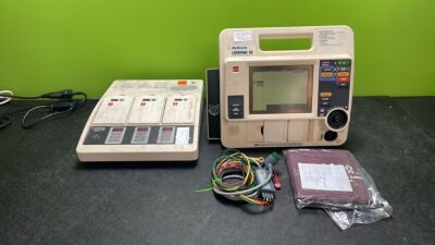 Job Lot Including 1 x Medtronic Physio Control Lifepak 12 Biphasic Defibrillator / Monitor Including ECG and Printer Options with 1 x Physio Control Battery Support System 2 Charger,3 x Batteries, 1 x 4 Lead ECG Lead (Both Powers Up - 3 x Flat Batteries I