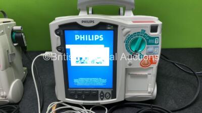 2 x Philips Heartstart MRx Defibrillators Including ECG and Printer Options with 2 x M3725A Test Loads, 2 x Paddle Leads, 1 x ECG Lead, 1 x Battery and 1 x M33539A Module (Both Power Up, 1 x Slight Damage to Casing - See Photos) - 2