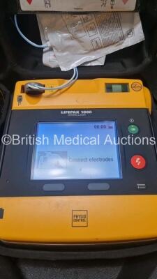 2 x Medtronic Physio Control Lifepak 1000 Defibrillators *Mfd 2016 / 2018* (Both Power Up) with 2 x 3 Lead ECG Lead , 3 x in Date Electrode Packs and 3 x Physio Control 1000 Batteries *Li/Mn02* - 2