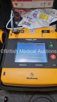 2 x Medtronic Physio Control Lifepak 1000 Defibrillators *Mfd 2008 / 2009* (Both Power Up 1 x Crack In Screen - See Photo) with 2 x 3 Lead ECG Lead , 2 x in Date Electrode Packs and 3 x Physio Control 1000 Batteries *Li/Mn02* - 2