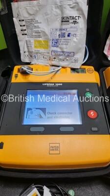 2 x Medtronic Physio Control Lifepak 1000 Defibrillators *Mfd 2008 / 2018* (Both Power Up) with 2 x 3 Lead ECG Lead , 3 x in Date Electrode Packs and 3 x Physio Control 1000 Batteries *Li/Mn02* - 3