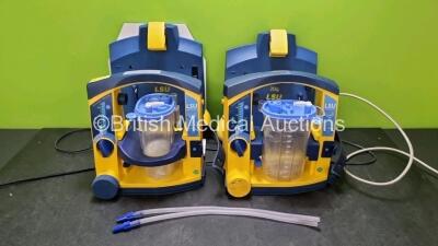 2 x LSU Laerdal Suction Units (Both Power Up, 1 x with Damage to Casing - See Photo) with, 2 x Suction Cups, 2 x LSU Wall Mounting Bracket, 2 x Batteries and 2 x Hoses