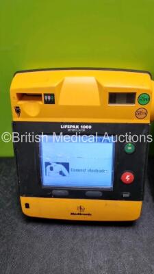 2 x Medtronic Physio Control Lifepak 1000 Defibrillators *Mfd 2009* (1 x No Power, 1 x Powers Up with Stock Battery Stock Battery Not Included, Both with Damage to Casing and Screen- See Photos) - 2