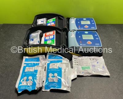 2 x Laerdal Heartstart FR2+ Defibrillators with 4 x Batteries and 3 x Electrode Packs *2 in Date, 1 Expired* in Carry Cases (Both Power Up)