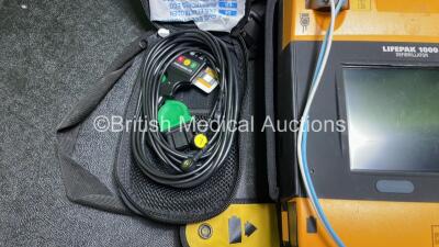 2 x Medtronic Physio Control Lifepak 1000 Defibrillators (Both Power Up with Cracks in Casing - See Photos) with 2 x 3 Lead ECG Leads, 3 x Electrode Packs (All in Date) and 2 x Batteries *Install Before 2024 / 2024* - 7