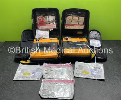 2 x Medtronic Physio Control Lifepak 1000 Defibrillators (Both Power Up with Cracks in Casing - See Photos) with 2 x 3 Lead ECG Leads, 4 x Electrode Packs (3 in Date, 1 x Expired) and 2 x Batteries *Install Before 2022 / 2025*