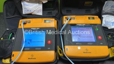 2 x Medtronic Physio Control Lifepak 1000 Defibrillators (Both Power Up with Cracks in Casing - See Photos) with 2 x 3 Lead ECG Leads, 4 x Electrode Packs (3 in Date, 1 x Expired) and 2 x Batteries *Install Before 2022 / 2025* - 2