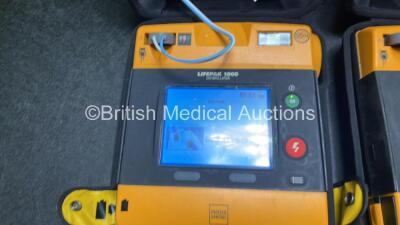 2 x Medtronic Physio Control Lifepak 1000 Defibrillators (Both Power Up with Cracks in Casing - See Photos) with 2 x 3 Lead ECG Leads, 4 x Electrode Packs (All in Date) and 2 x Batteries *Install Before 2022 / 2025* - 3