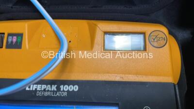 2 x Medtronic Physio Control Lifepak 1000 Defibrillators (Both Power Up with Cracks in Casing - See Photos) with 2 x 3 Lead ECG Leads, 4 x Electrode Packs (All in Date) and 2 x Batteries *Install Before 2022 / 2025* - 4