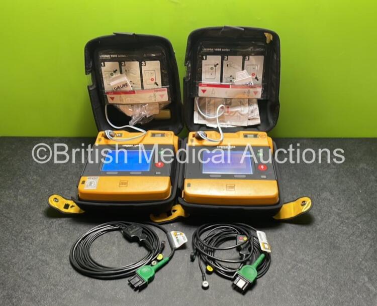 2 x Medtronic Physio Control Lifepak 1000 Defibrillators (Both Power Up with Cracks in Casing - See Photos ) with 2 x 3 Lead ECG Leads, 4 x Electrode Packs (All in Date) and 2 x Batteries *Install Before 2024 / 2024*