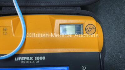 2 x Medtronic Physio Control Lifepak 1000 Defibrillators (Both Power Up with Cracks in Casing - See Photos ) with 2 x 3 Lead ECG Leads, 4 x Electrode Packs (All in Date) and 2 x Batteries *Install Before 2024 / 2024* - 6