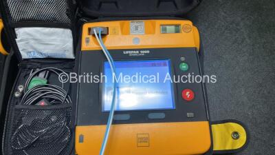 2 x Medtronic Physio Control Lifepak 1000 Defibrillators (Both Power Up, 1 x Small Crack in Casing, 1 x Slight Damage to Casing - See Photos ) with 2 x 3 Lead ECG Leads, 4 x Electrode Packs (All in Date) and 2 x Batteries *Install Before 2028 / 2024* - 4