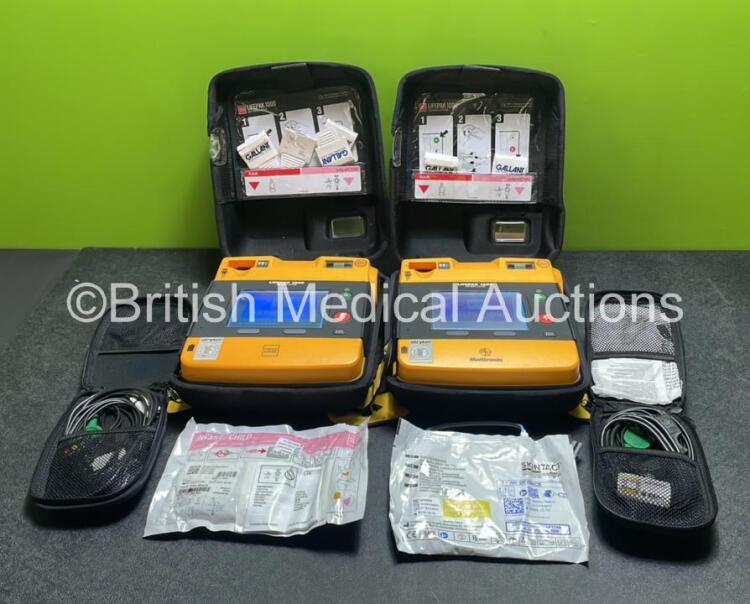 2 x Medtronic Physio Control Lifepak 1000 Defibrillators (Both Power Up, 1 x Small Crack In Casing - See Photos) with 2 x ECG Leads, 2 x Electrode Packs (Both in Date) and 2 x Batteries *Install Before 2024 / 2024* in Carry Cases