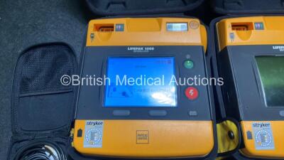 2 x Medtronic Physio Control Lifepak 1000 Defibrillators (Both Power Up, 1 x Small Crack In Casing - See Photos) with 2 x ECG Leads, 2 x Electrode Packs (Both in Date) and 2 x Batteries *Install Before 2024 / 2024* in Carry Cases - 4