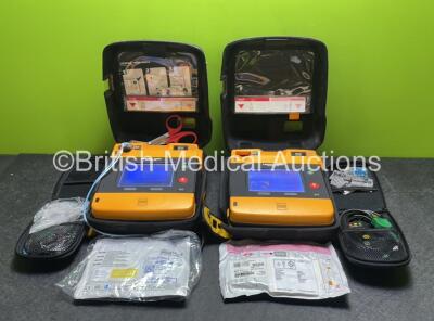 2 x Medtronic Physio Control Lifepak 1000 Defibrillators (Both Power Up with Cracks In Casing - See Photos) with 2 x ECG Leads, 2 x Electrode Packs (Both in Date) and 2 x Batteries *Install Before 2025 / 2024* in Carry Cases