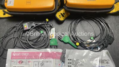 2 x Medtronic Physio Control Lifepak 1000 Defibrillators (Both Power Up with Cracks In Casing - See Photos) with 2 x ECG Leads, 2 x Electrode Packs (1 in Date, 1 Expired) and 2 x Batteries *Install Before 2025 / 2024* in Carry Cases - 7