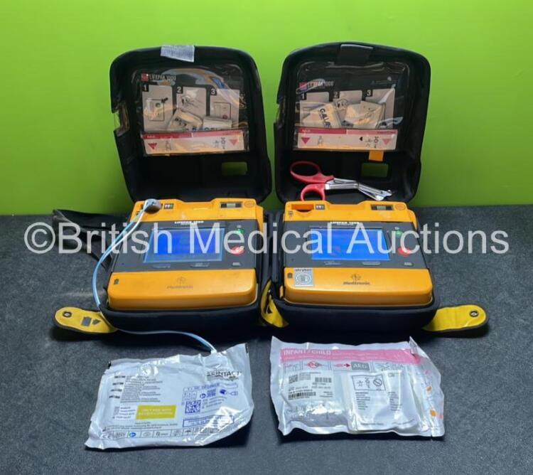 2 x Medtronic Physio Control Lifepak 1000 Defibrillators (Both Power Up with Cracks In Casing - See Photos) with 2 x Electrode Packs (Both In Date) and 2 x Batteries *Install Before 2025 / 2026* in Carry Cases