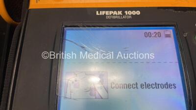 2 x Medtronic Physio Control Lifepak 1000 Defibrillators (Both Power Up with Cracks In Casing - See Photos) with 2 x Electrode Packs (Both In Date) and 2 x Batteries *Install Before 2025 / 2026* in Carry Cases - 3